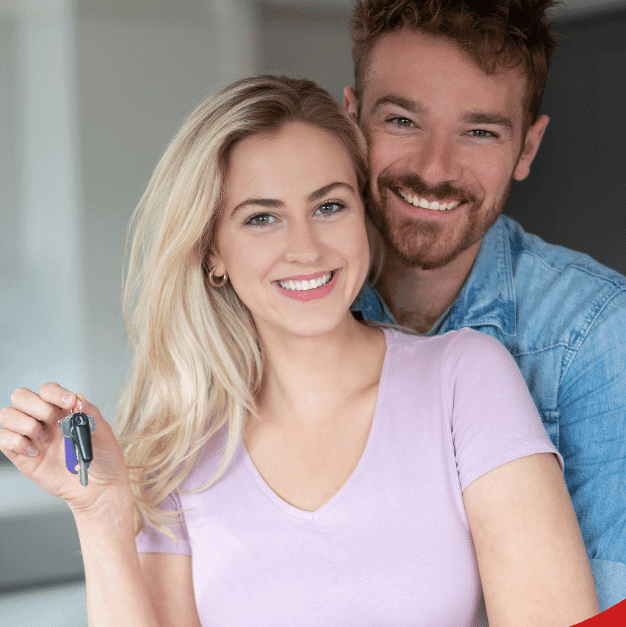 Happy young couple in a modern kitchen, with the woman holding house keys.
