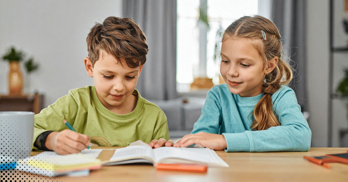 Young boy and girl studying together at a table in a cozy room.