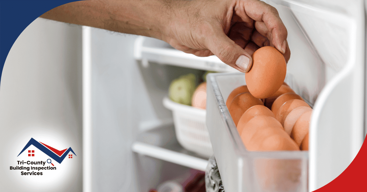 Hand taking an egg from a refrigerator door shelf.