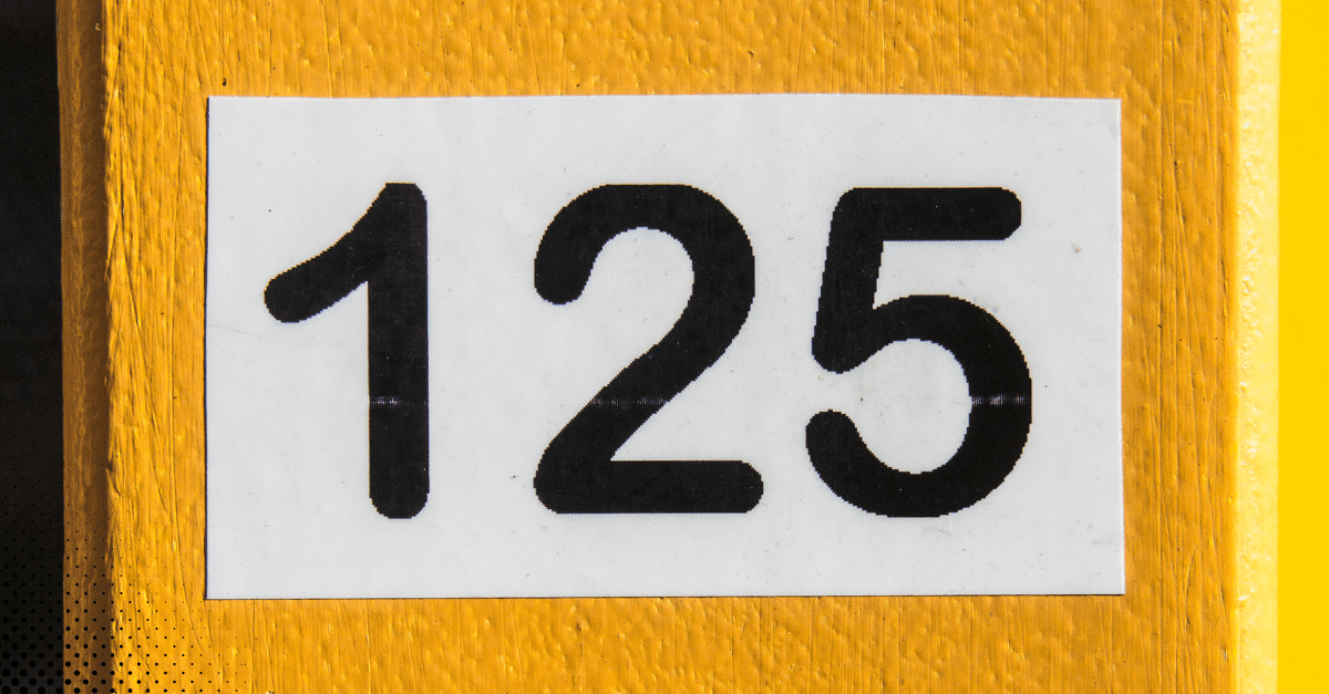 Black house number 125 on a white background attached to a yellow post