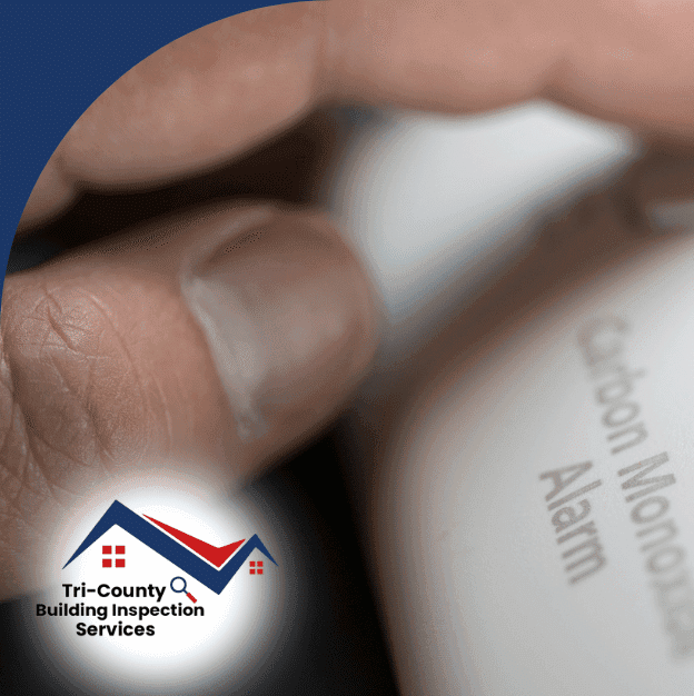 Finger pressing the test/reset button on a carbon monoxide alarm.