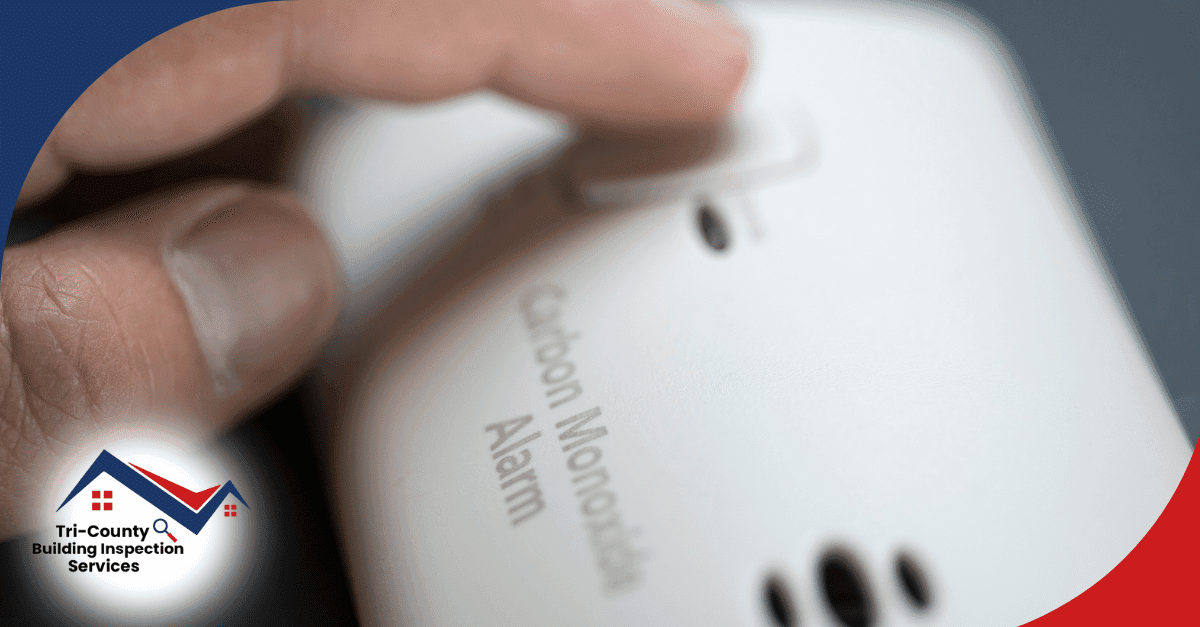 Finger pressing the test/reset button on a carbon monoxide alarm.