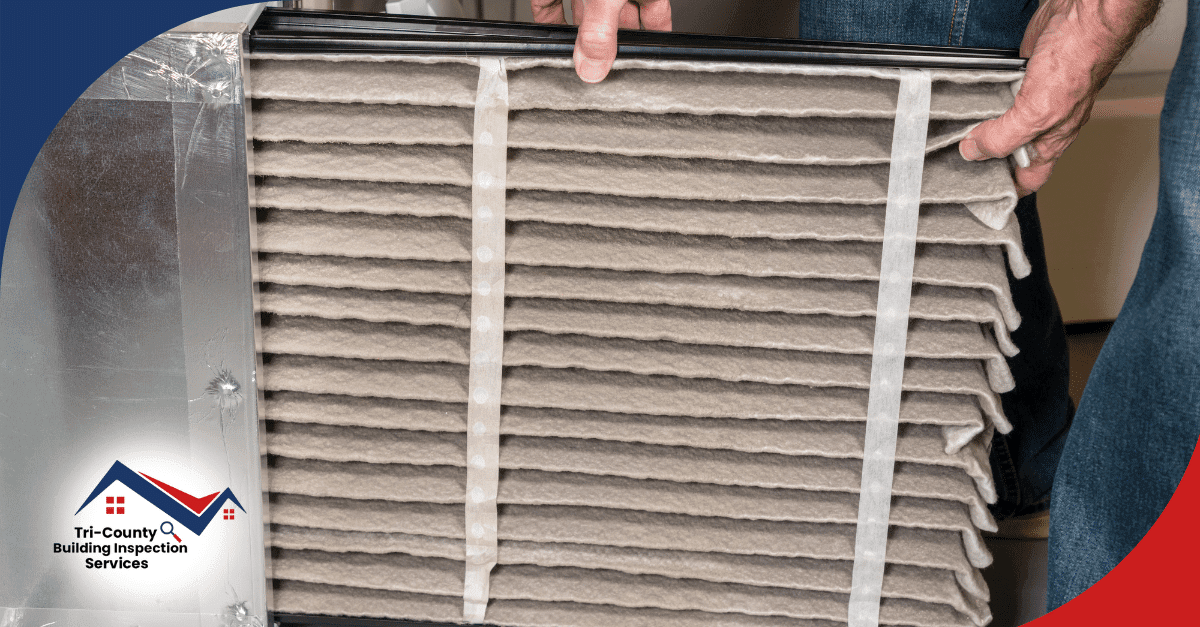 Inspector reviewing a dirty HVAC air filter inside the system.